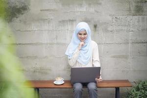 Muslim woman with hijab is working with laptop computer in coffee shop photo