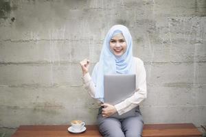 Muslim woman with hijab is working with laptop computer in coffee shop photo