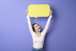 Young woman is holding yellow empty speech on purple background photo