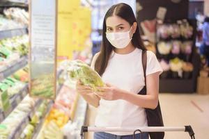 mujer está comprando en el supermercado con mascarilla