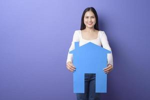 el retrato de una mujer hermosa sostiene una casa azul con un fondo morado foto