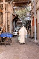 Rear view of old man in traditional djellaba walking on street photo