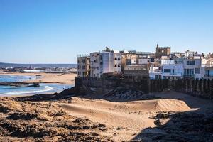 City skyline with rock formations at beach in sunny day against blue sky photo