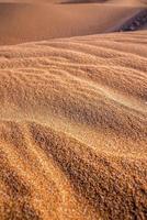 Beautiful shiny brown sand with natural waves pattern on sunny day photo