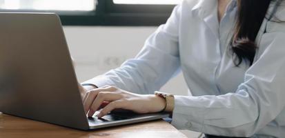 cerrar las manos de las mujeres de negocios jóvenes usando una computadora portátil en la oficina en casa