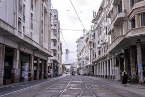 Tranvía a través de edificios con torre de reloj en segundo plano en día soleado foto