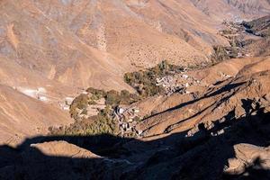 Scenic landscape of village flanked by mountains in sunlight photo