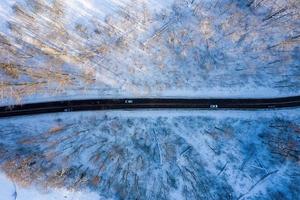 Curvy windy road in snow covered forest, top down aerial view. photo