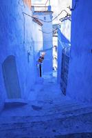 Narrow alley of blue town with staircase leading to residential structures on both side photo