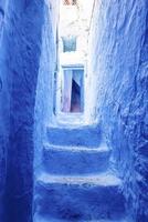 Narrow alley of staircase leading to open door of traditional blue residential structure photo