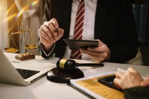 Business and lawyers discussing contract papers with brass scale on desk in office. Law, legal services, advice,  justice and law concept . photo