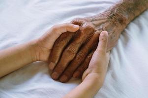 manos del anciano y la mano de un niño en la habitación foto