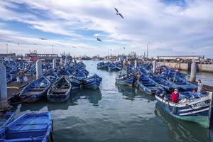 Barcos de pesca azules de madera anclados en el puerto deportivo contra el cielo nublado foto