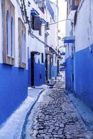 callejón estrecho con casas marroquíes tradicionales pintadas en color azul y blanco foto