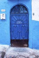 entrada de arco de una casa tradicional con pared azul y puerta metálica cerrada
