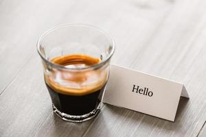 Fresh brewed Espresso coffee in shot glass on wooden table