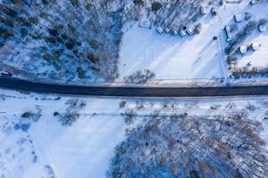 Curvy windy road in snow covered forest, top down aerial view. photo
