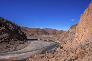 Dry river flowing through mountains against clear sky in summer photo