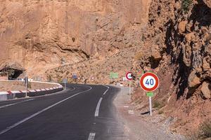 carretera asfaltada con marcas y señales de límite de velocidad a través de la montaña foto