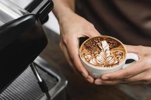 Hands of barista holding a cup of Latte coffee about to serve in cafe photo