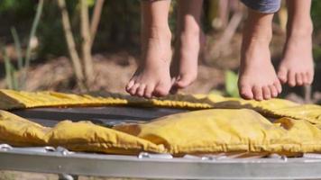 Nahaufnahme der Füße eines Kindes, die beim Spielen im Hof auf einem kleinen Trampolin hoch springen. Kinder spielen Trampolin auf dem Spielplatz.