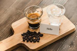 Fresh brewed black Espresso coffee and water in shot glasses served on wooden platter ready to drink photo