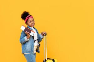 Traveling African American girl wih baggage passport and boarding pass isolated on yellow background with copy space photo