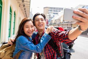 Young Asian tourist girl taking selfie with boyfriend during summer vacations in Bangkok city Thailand photo