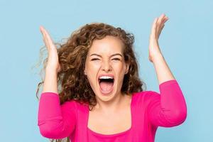 Shocked angry young Caucasian woman shouting isolated on light blue studio background photo