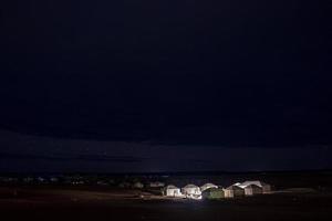 Glowing tourist tents on sand in desert landscape during night photo