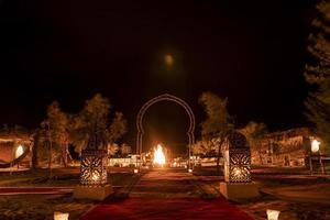 linternas iluminadas junto a la alfombra en la arena en el desierto contra el cielo durante la noche foto