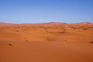 Impresionante vista de las dunas de arena con patrón de ondas en el desierto contra el cielo azul foto