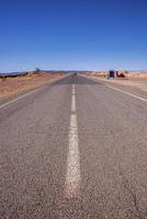 Straight asphalt road with markings through desert against sky photo