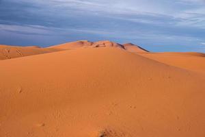 Impresionante vista de las dunas de arena con patrón de ondas en el desierto contra el cielo nublado foto