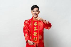un apuesto hombre asiático sonriente que muestra una etiqueta roja con texto significa que puede obtener una mayor riqueza en un estudio aislado de fondo gris claro para los conceptos del año nuevo chino foto