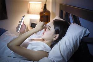 Woman is feeling eye pain when using smart phone at night photo
