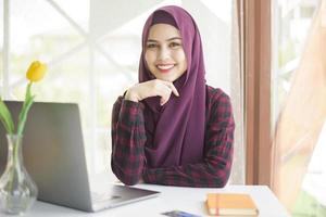 Muslim woman with hijab is working with laptop computer in coffee shop photo