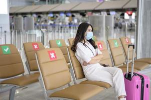A traveller woman is wearing protective mask in International airport, travel under Covid-19 pandemic, safety travels, social distancing protocol, New normal travel concept photo