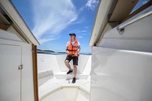 tourist in life jacket enjoying and relaxing on speedboat with a beautiful view of ocean and mountain in backgound photo