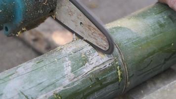 Close-up of sawing green bamboo with a chainsaw for use in traditional handicrafts.