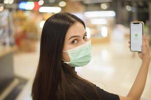 people hand is holding smartphone with Thaichana campaign of Thailand for COVID-19 prevention in shopping center photo