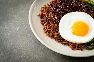 dried Korean spicy black sauce instant noodles with fried egg and kimchi photo