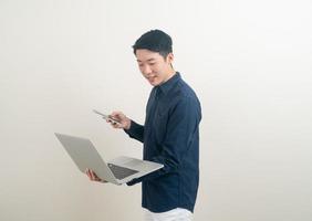 Asian man talking smartphone or mobile phone and hand holding laptop photo