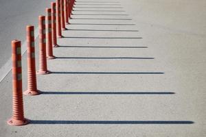 Red regilation poles throwing shadows on the road. photo