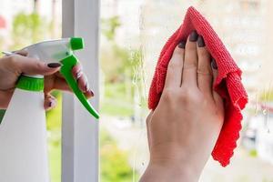 Woman sprays a detergent on a glass. photo