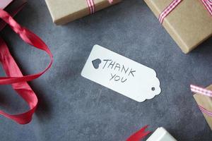 nota de agradecimiento y caja de regalo sobre fondo negro foto
