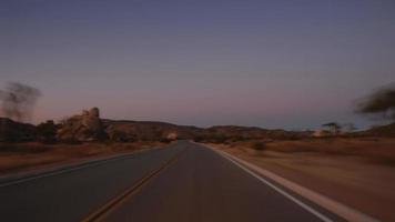 eine Zeitraffer-Fahrt auf einer Wüstenstraße in der Abenddämmerung