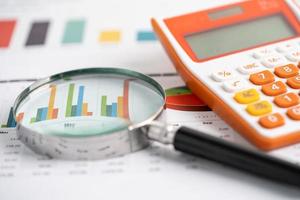 Magnifying glass and calculator on charts graphs paper. Financial development, Banking Account, Statistics, Investment Analytic research data economy, Stock exchange trading, Business office concept. photo
