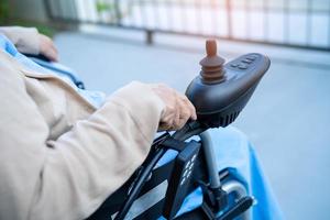 Paciente asiático mayor o anciano en silla de ruedas eléctrica con control remoto en la sala del hospital de enfermería, concepto médico fuerte y saludable