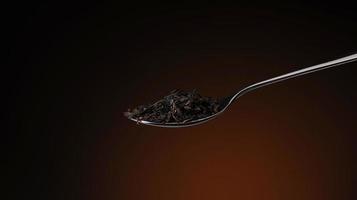 one spoon with tea leaves closeup on a burgundy background